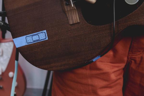 Close up of painters tape with an animation of band-aid on guitar
